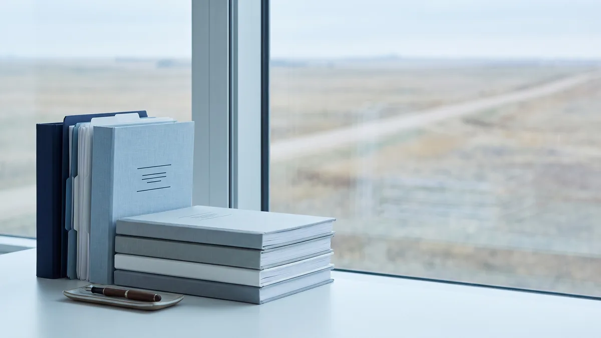 A law office desk with neatly stacked case files beside a window looking out on Nebraska scenery.