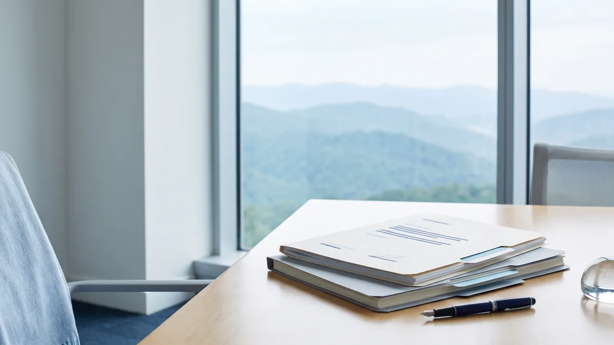 A law office desk with neatly stacked case files beside a window looking out on North Carolina scenery.