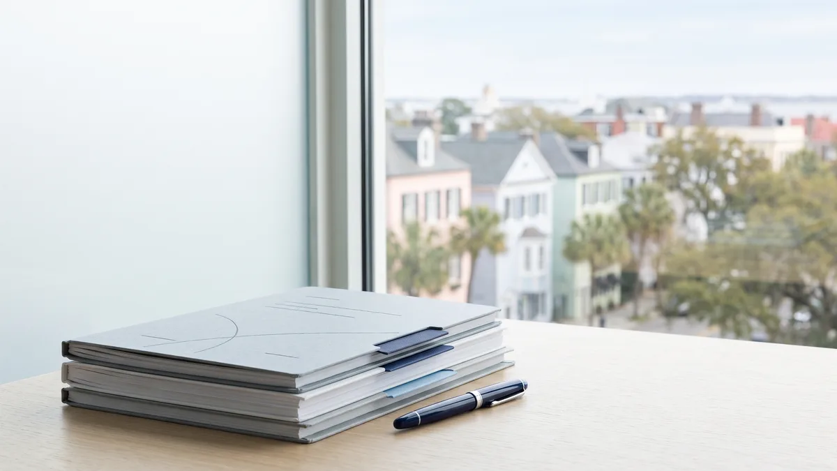 A law office desk with neatly stacked case files beside a window looking out on South Carolina scenery.